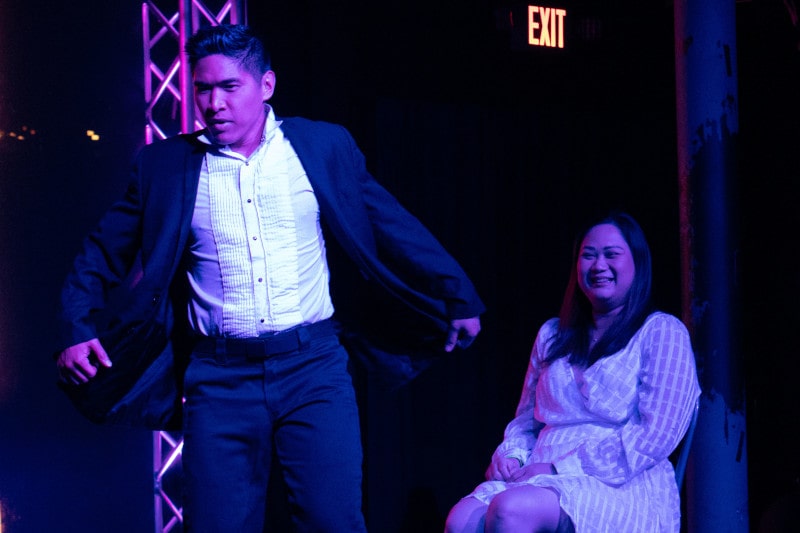 cesar dances in front of seated lady during man's world strip act